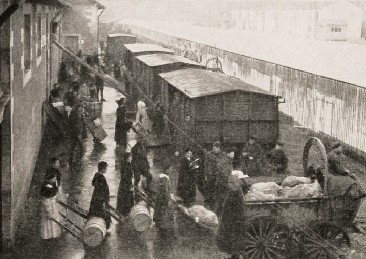 Supplies being loaded in a wheeled cart and several railcars.